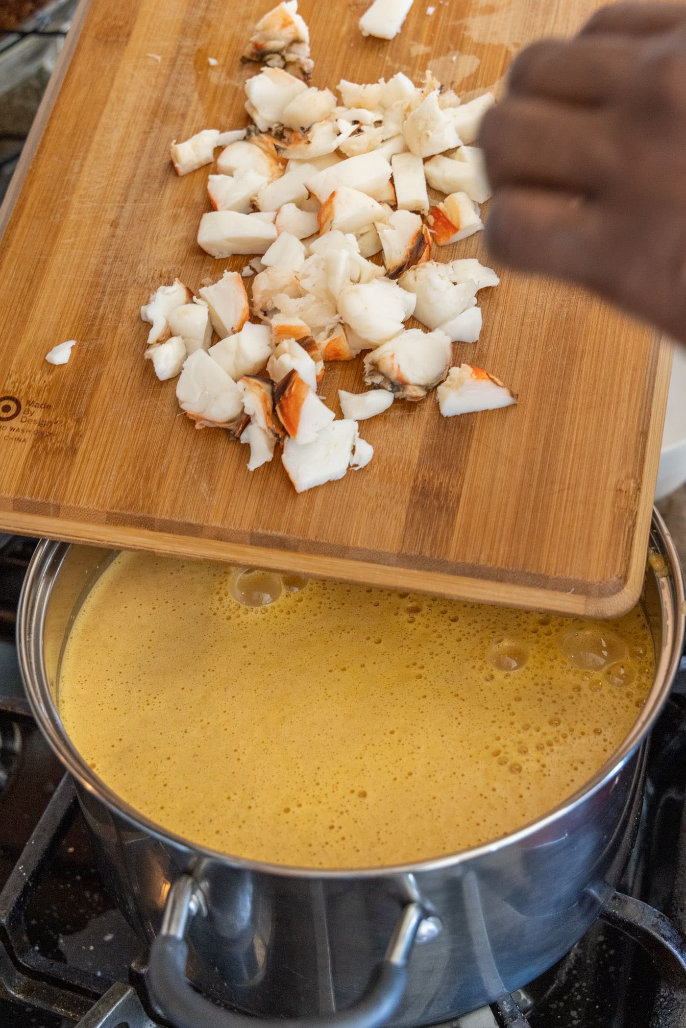 chopped lobster added to pot of bisque