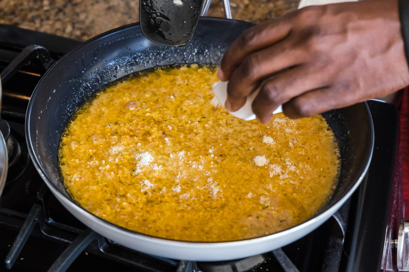 sprinkling parmesan cheese into thermidor sauce