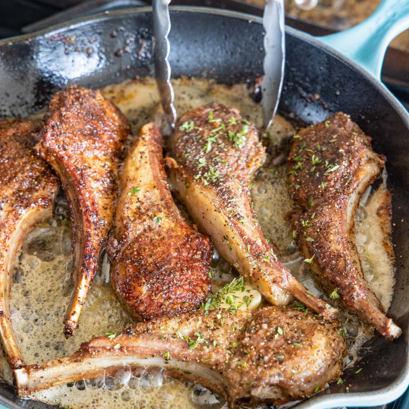 turning lamb in a skillet with butter