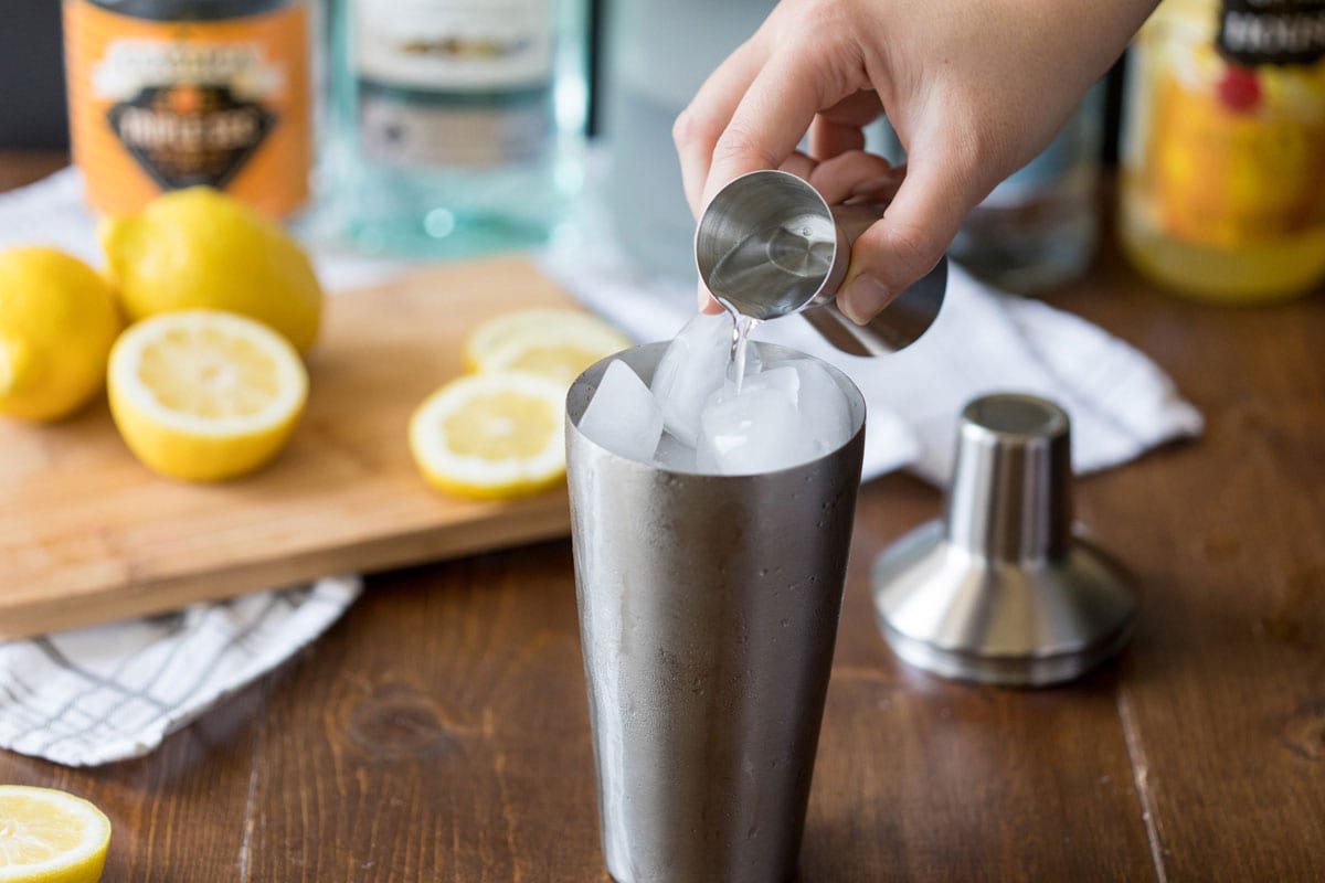 adding vodka to a cocktail shaker