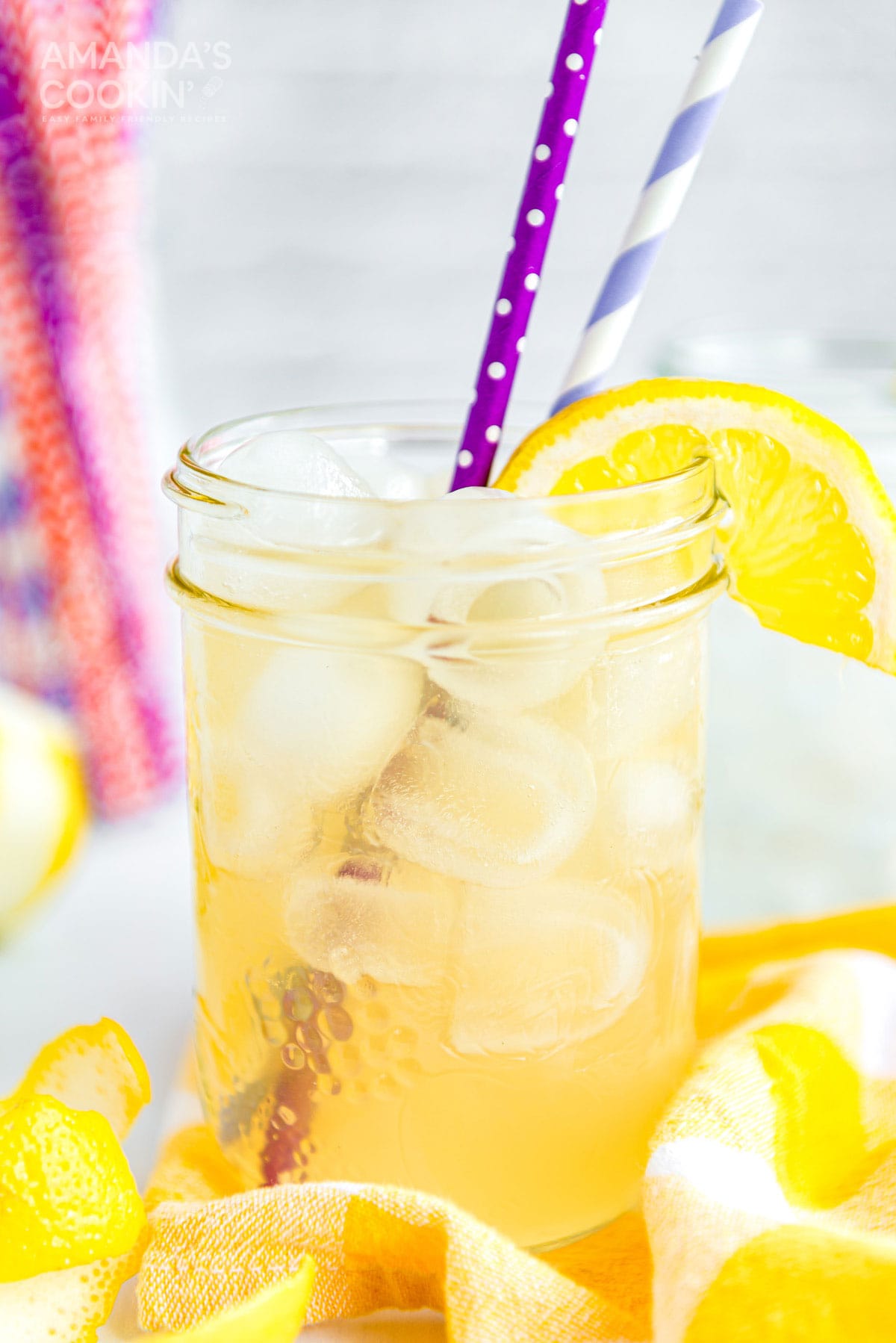 mason jar glass of lynchburg lemonade with straws and a lemon garnish
