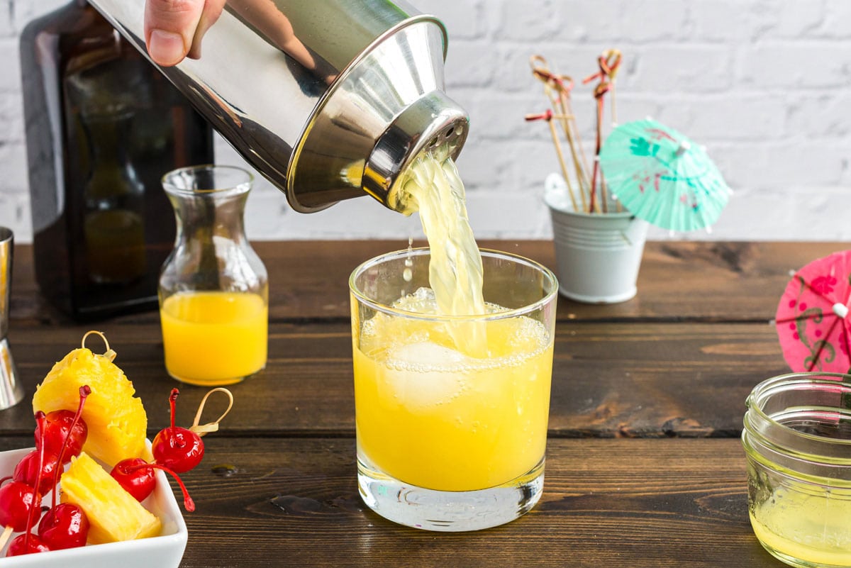 pouring mai tai out of cocktail shaker and into a glass