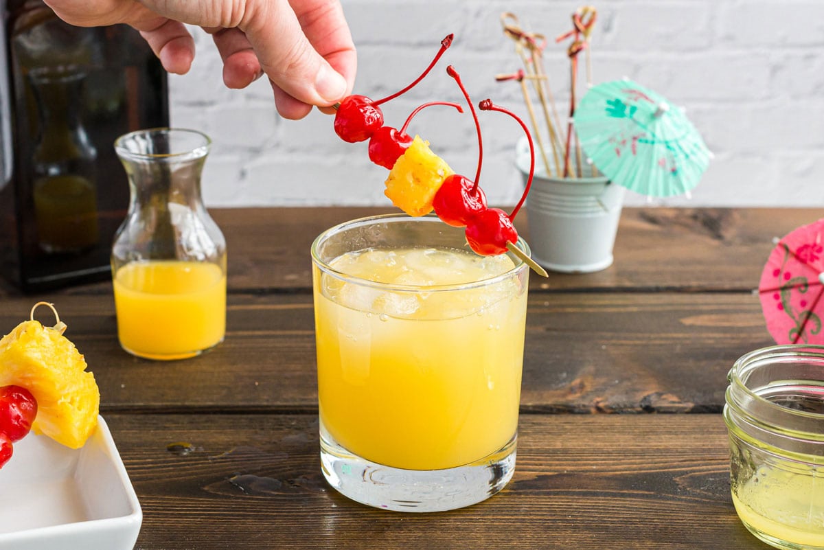 placing cherry and pineapple garnish on glass