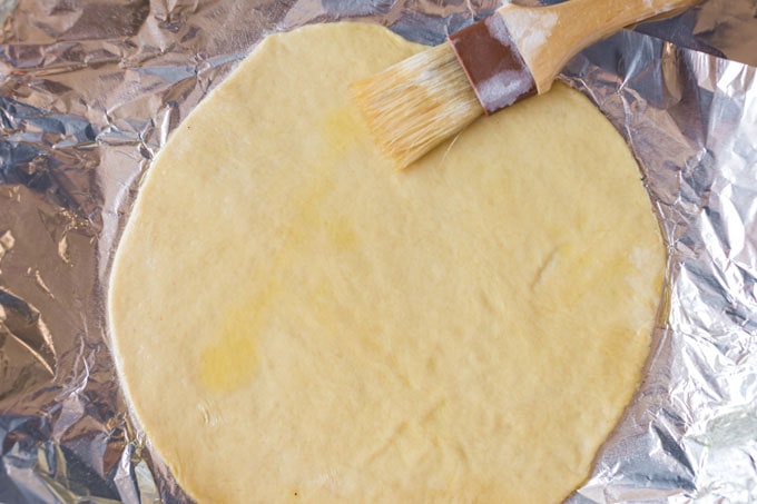 brushing olive oil on pizza dough