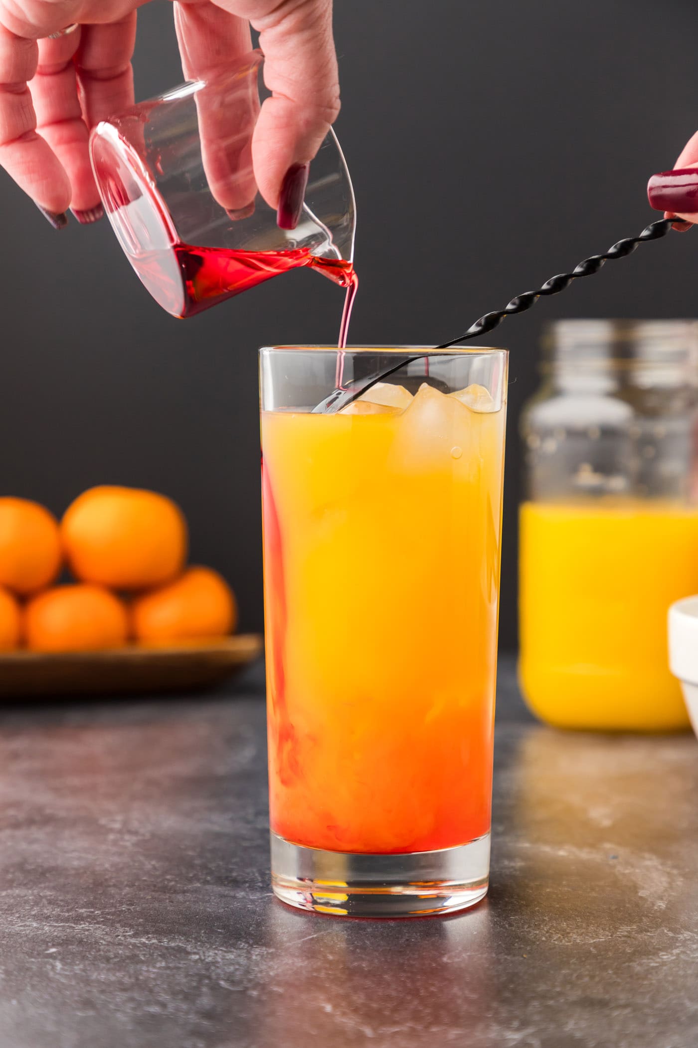 pouring grenadine over a spoon into malibu sunrise