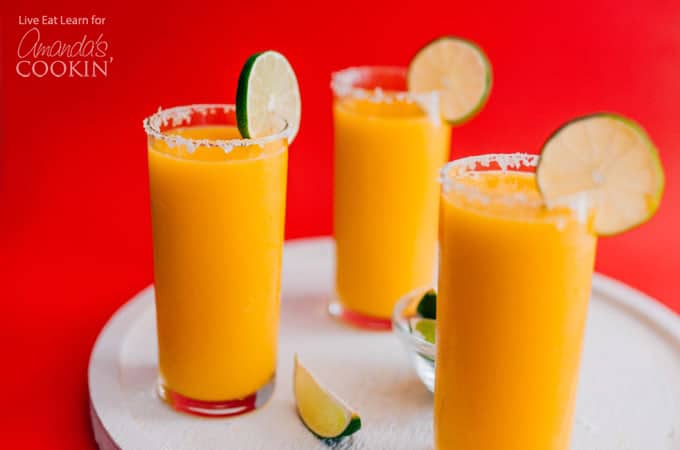 Mango Margarita Slush in glasses with a salted rim and lime garnish.