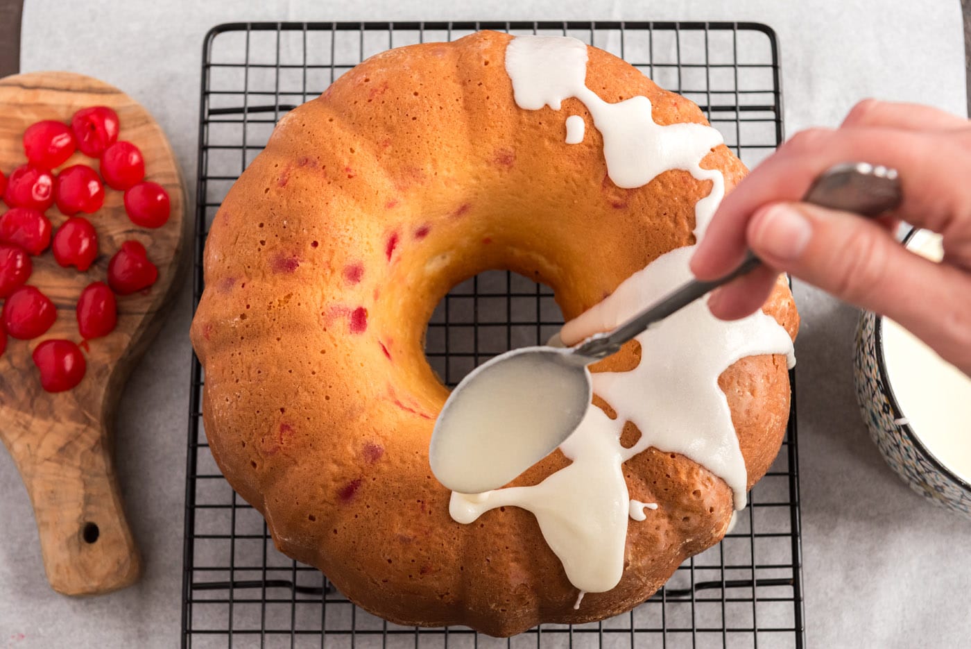 drizzling almond butter glaze over cherry bundt cake