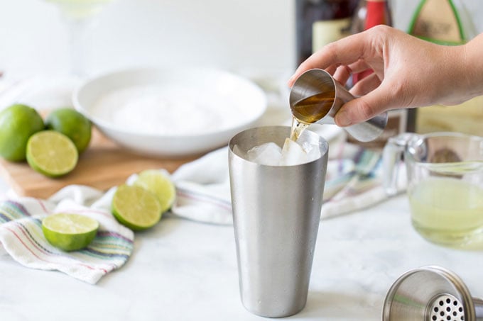 adding orange liqueur to cocktail shaker