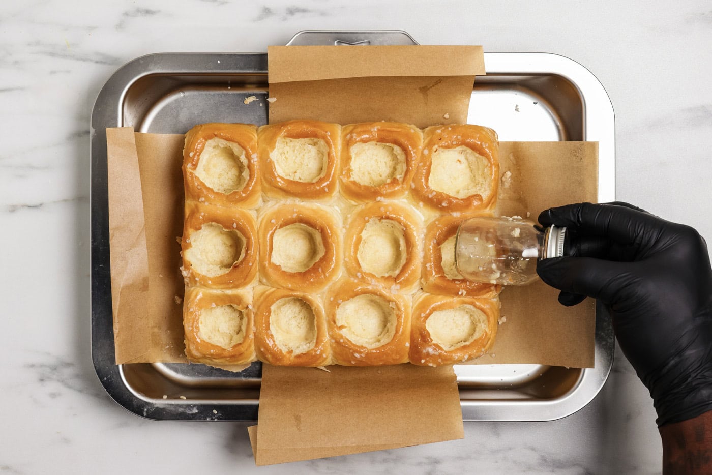 hand using a mason jar to create even holes inside bread rolls