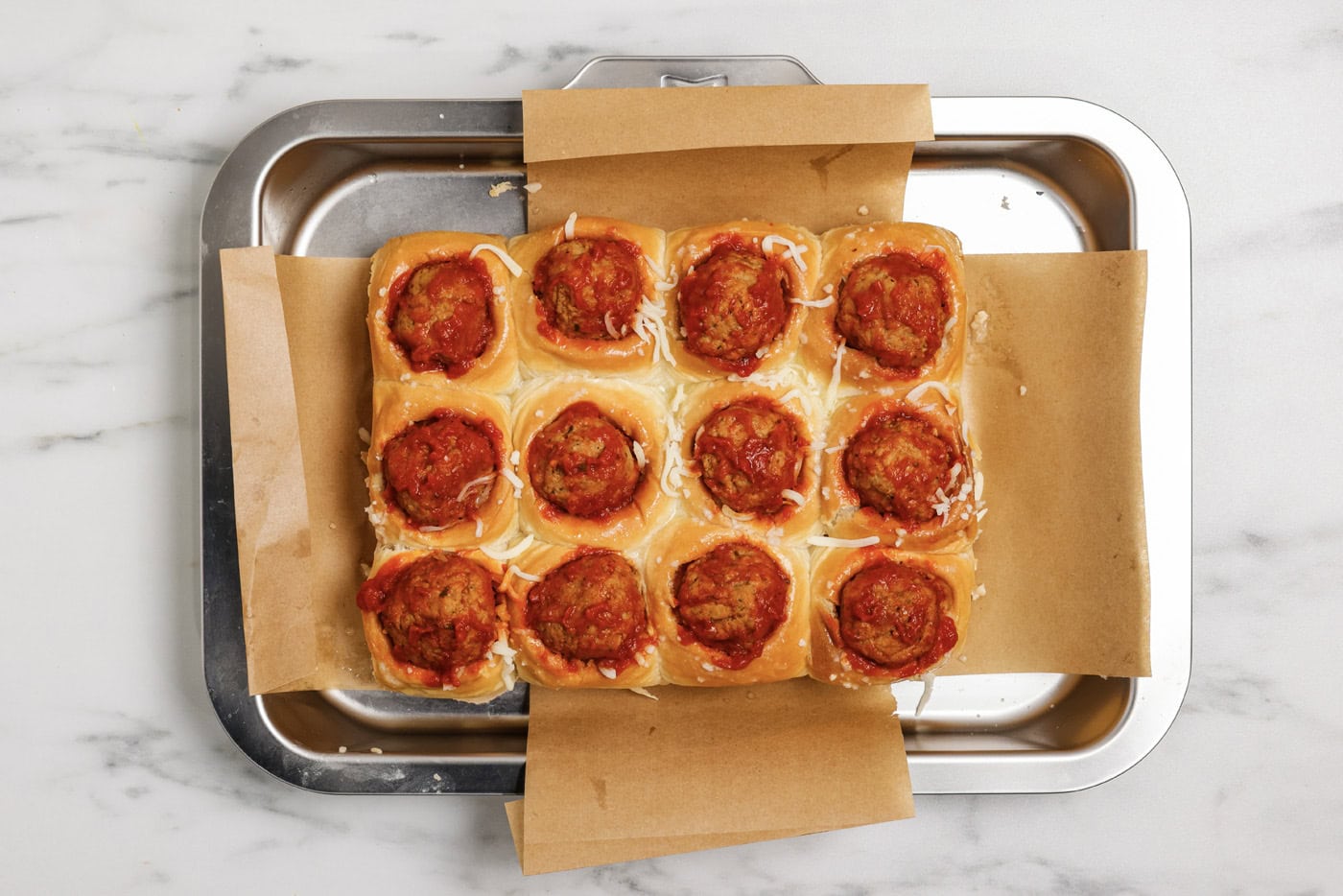 meatball and marinara sauce added on top of cheese and dinner rolls