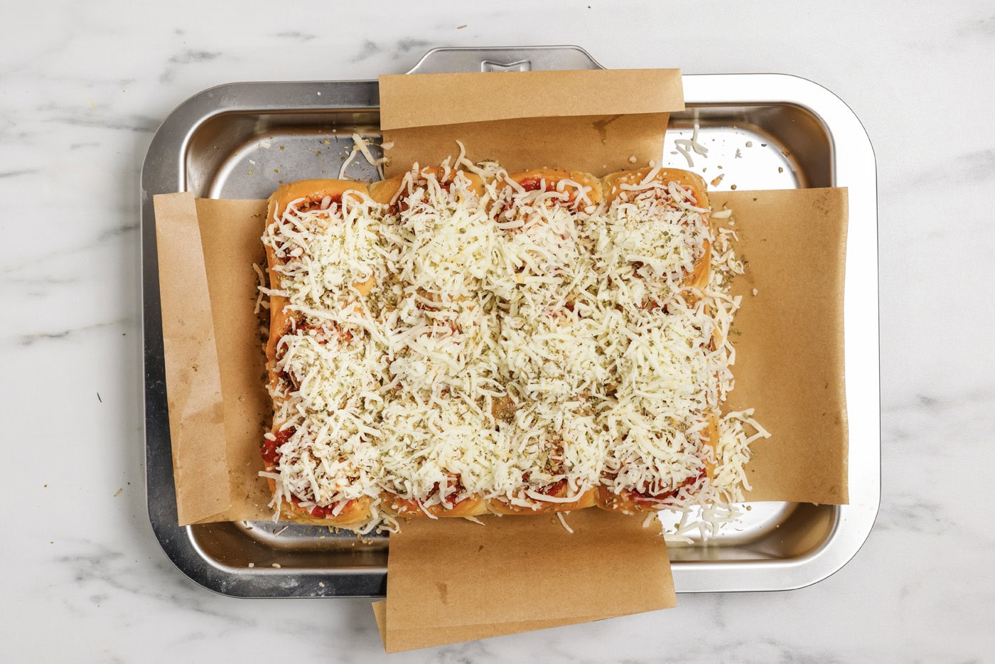 Shredded mozzarella cheese and parsley on top of meatball sliders