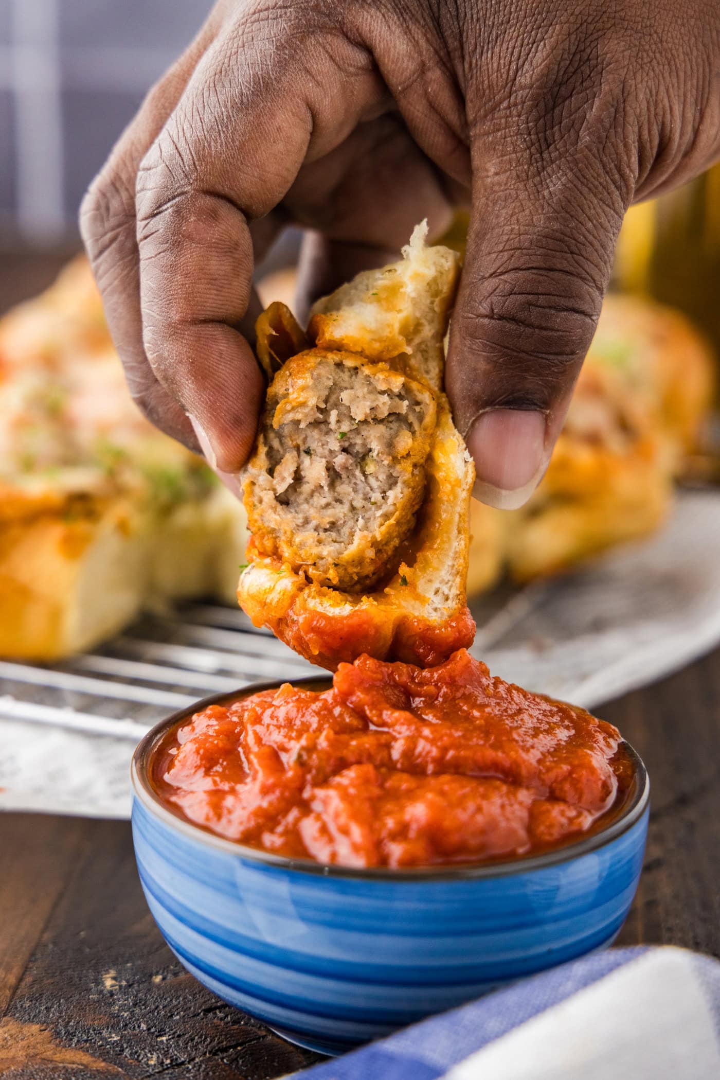 Meatball Slider being dipped into a bowl of marinara sauce