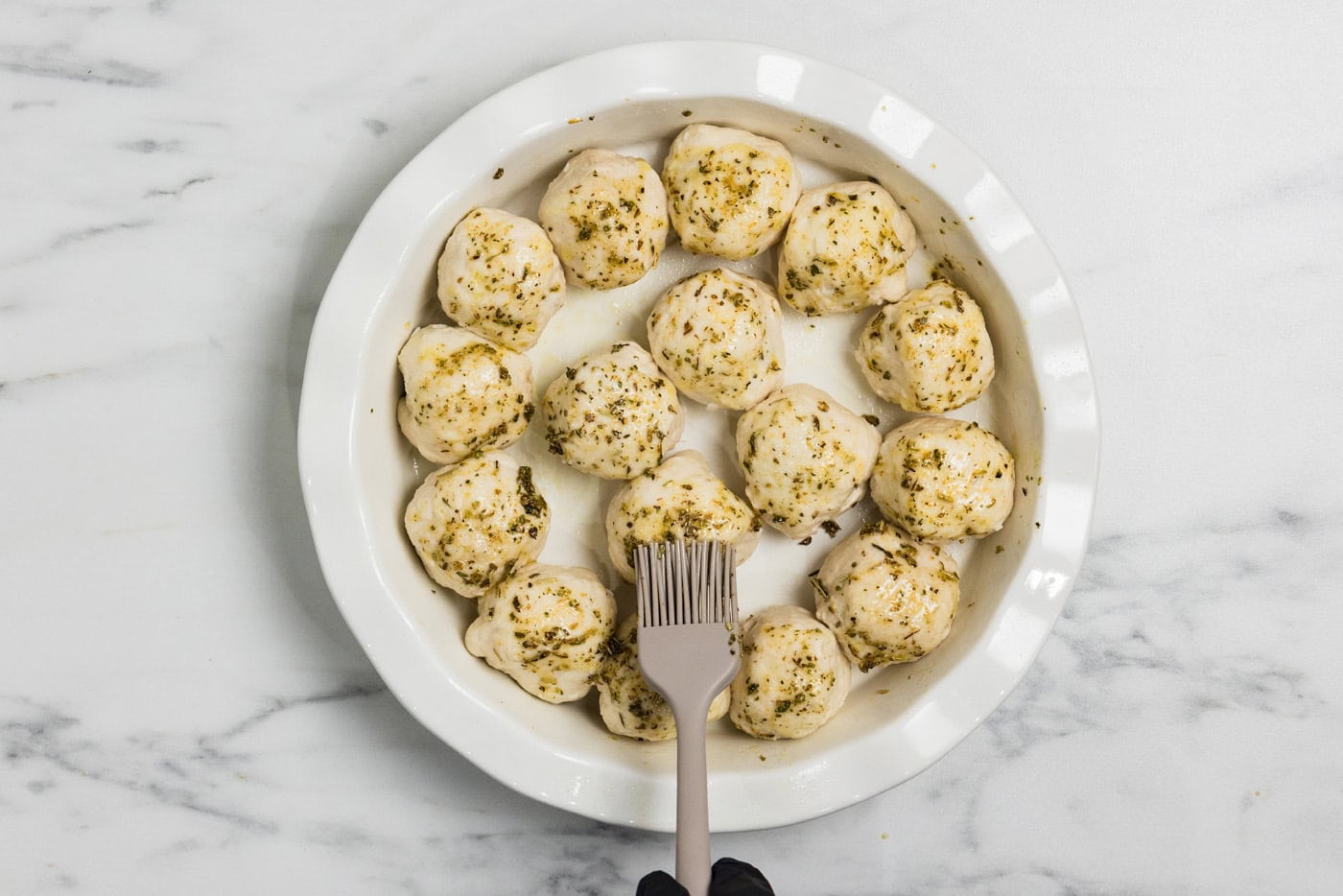 dough balls being brushed with seasoning and oil mixture