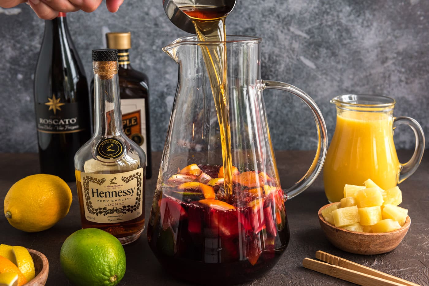 pouring brandy into red wine in a pitcher