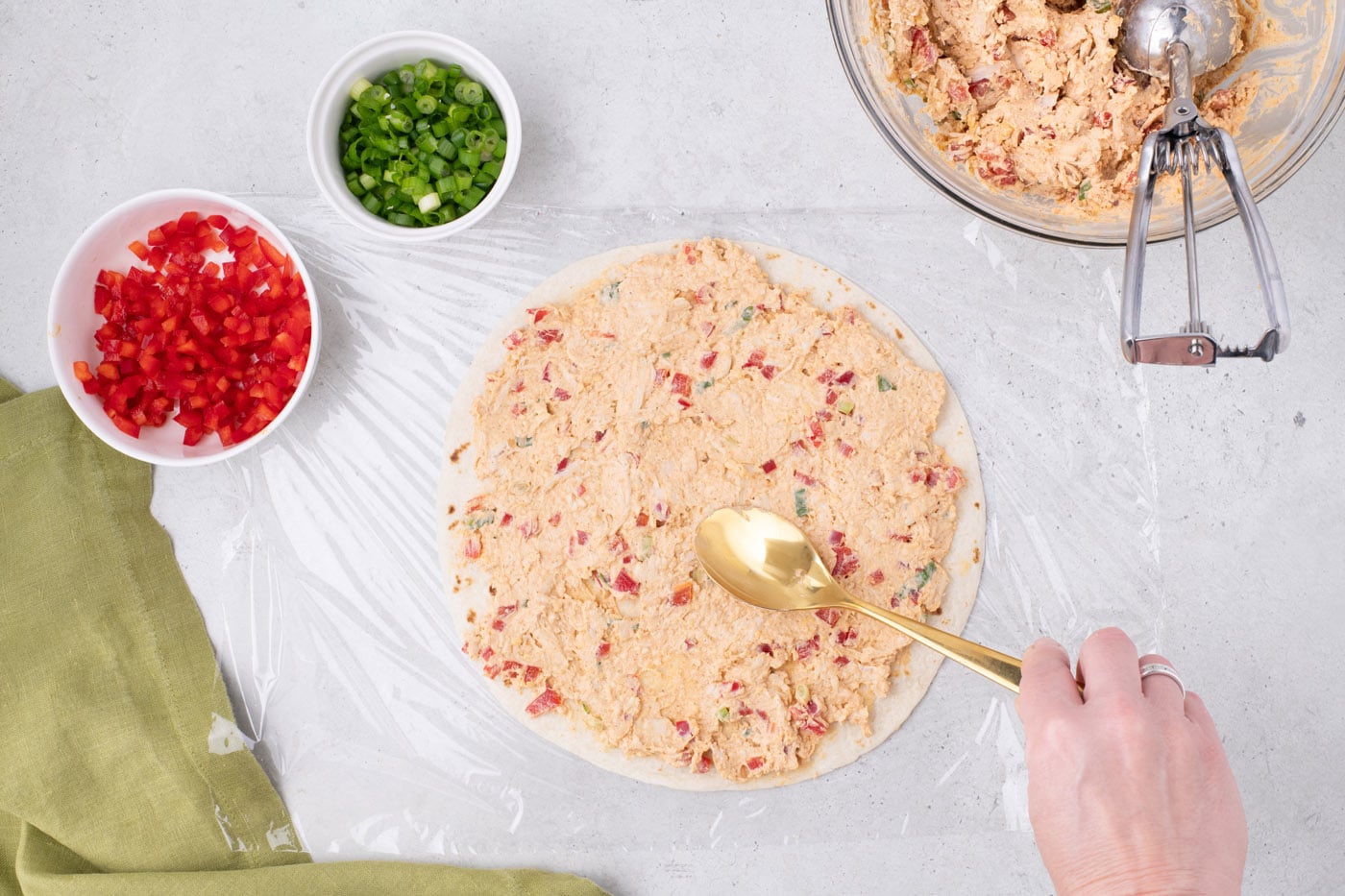 spreading cream cheese taco filling over a burrito tortilla shell