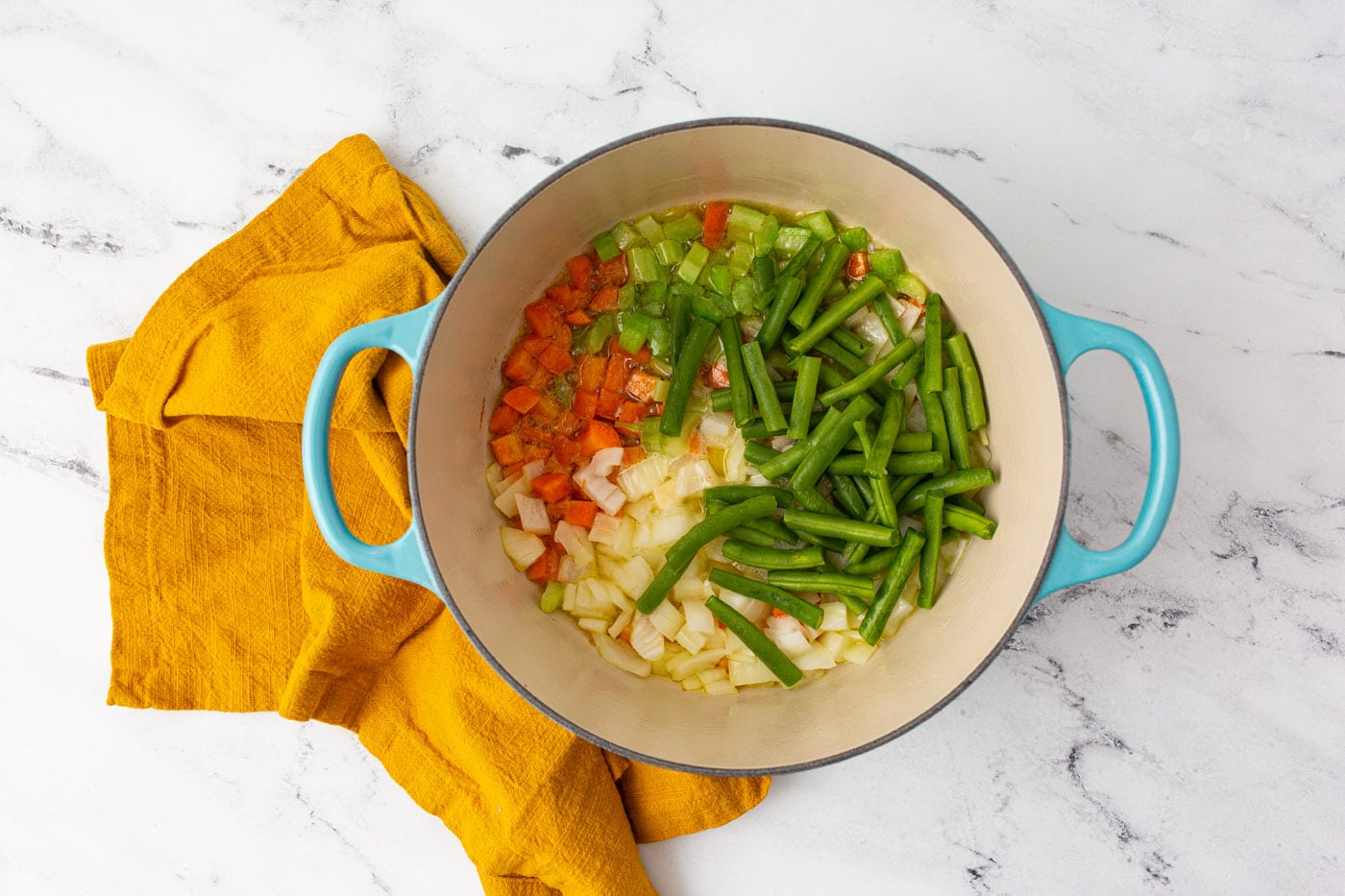 onions, carrots, celery, and green beans in a stockpot