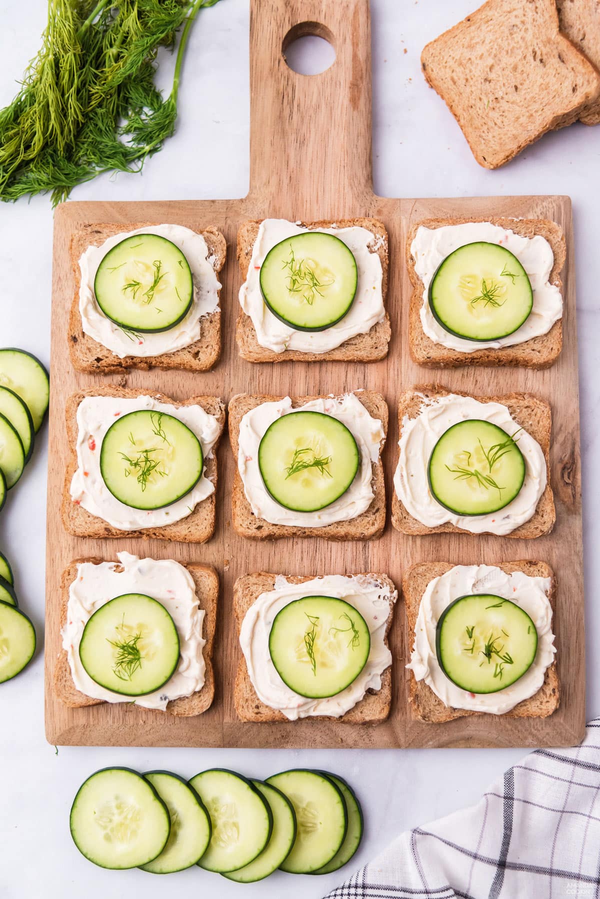 wood board with open faced cucumber sandwiches