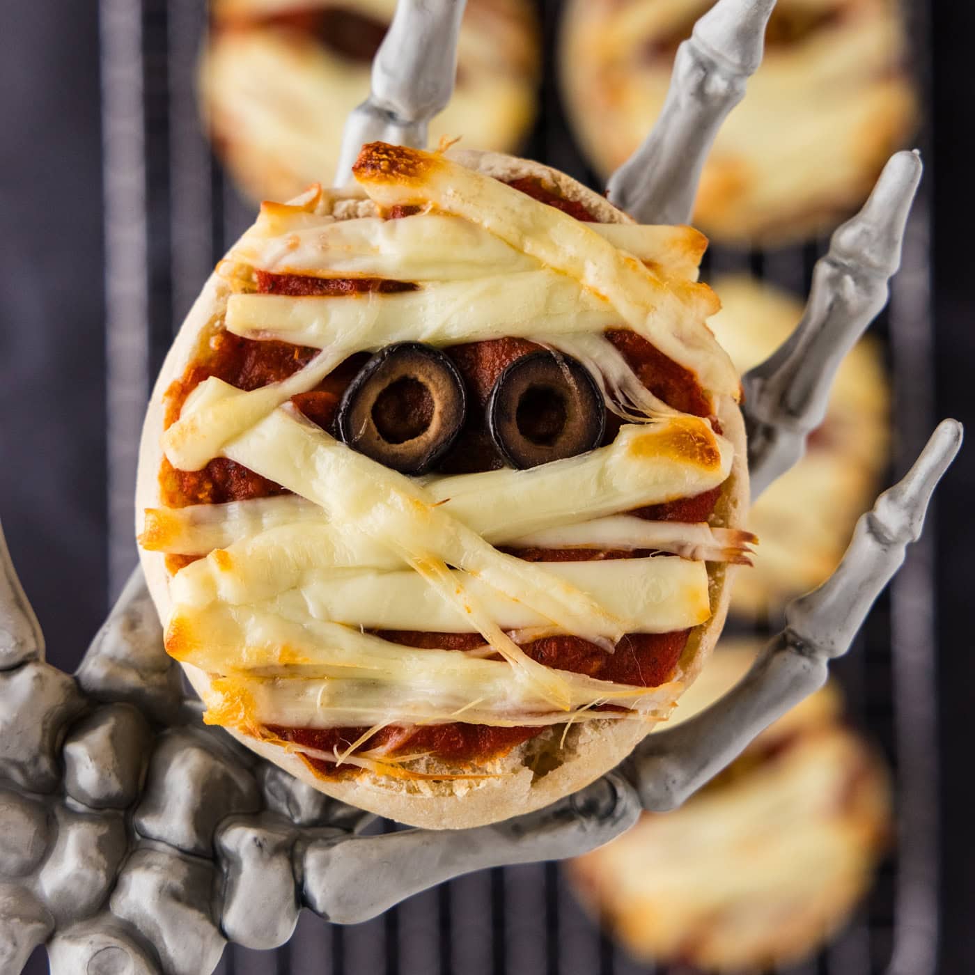 Close up photo of a Mini Mummy Pizza in a skeleton hand