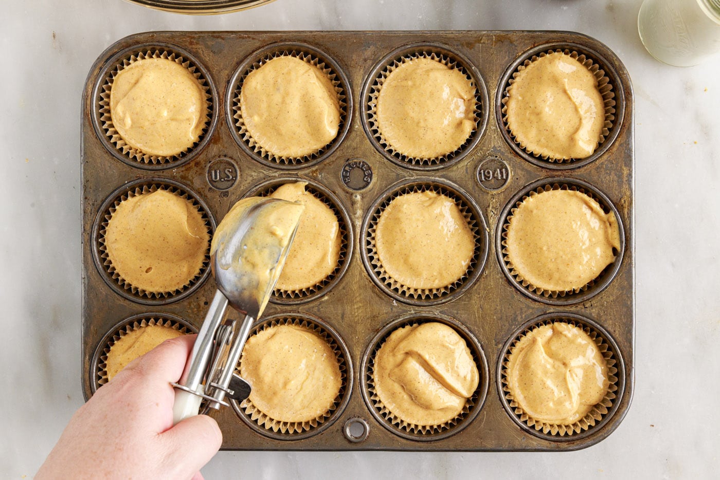 adding pumpkin cheesecake filling to a muffin tin