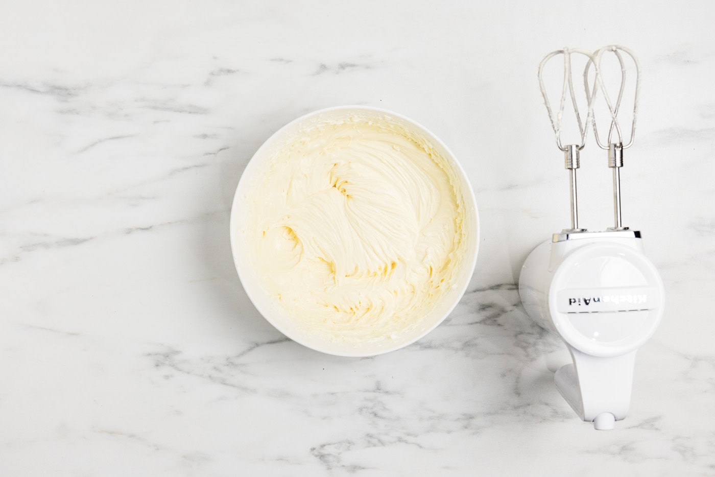 cheesecake batter in a bowl next to an electric mixer