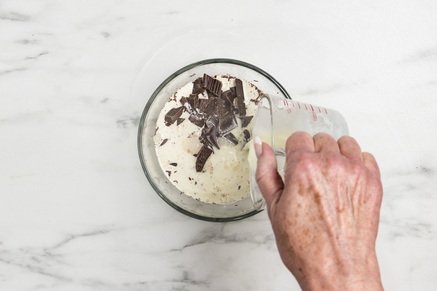 pouring hot cream over chopped chocolate in a bowl