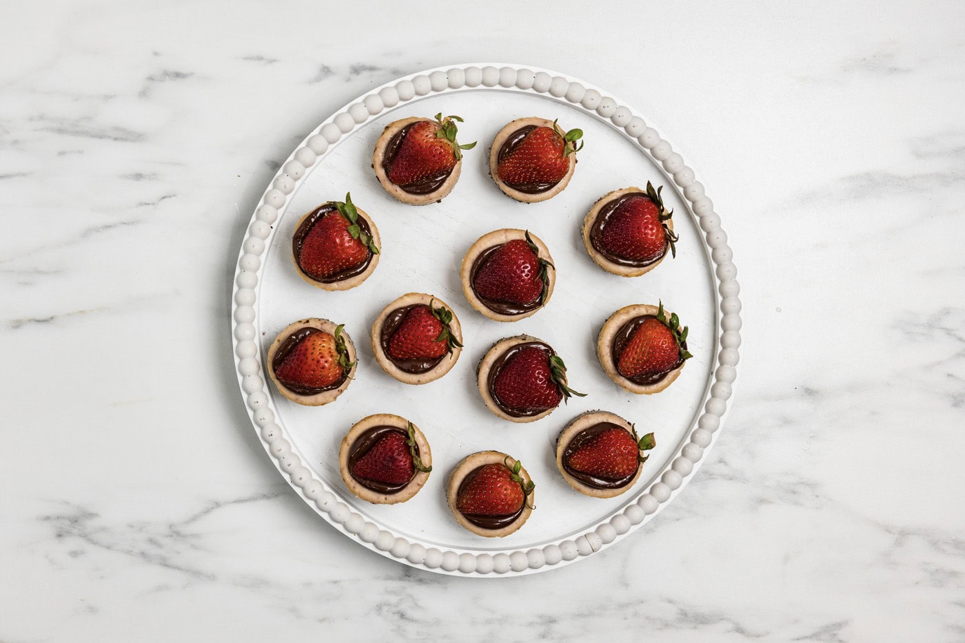 overhead of mini strawberry cheesecakes topped with ganache and strawberries