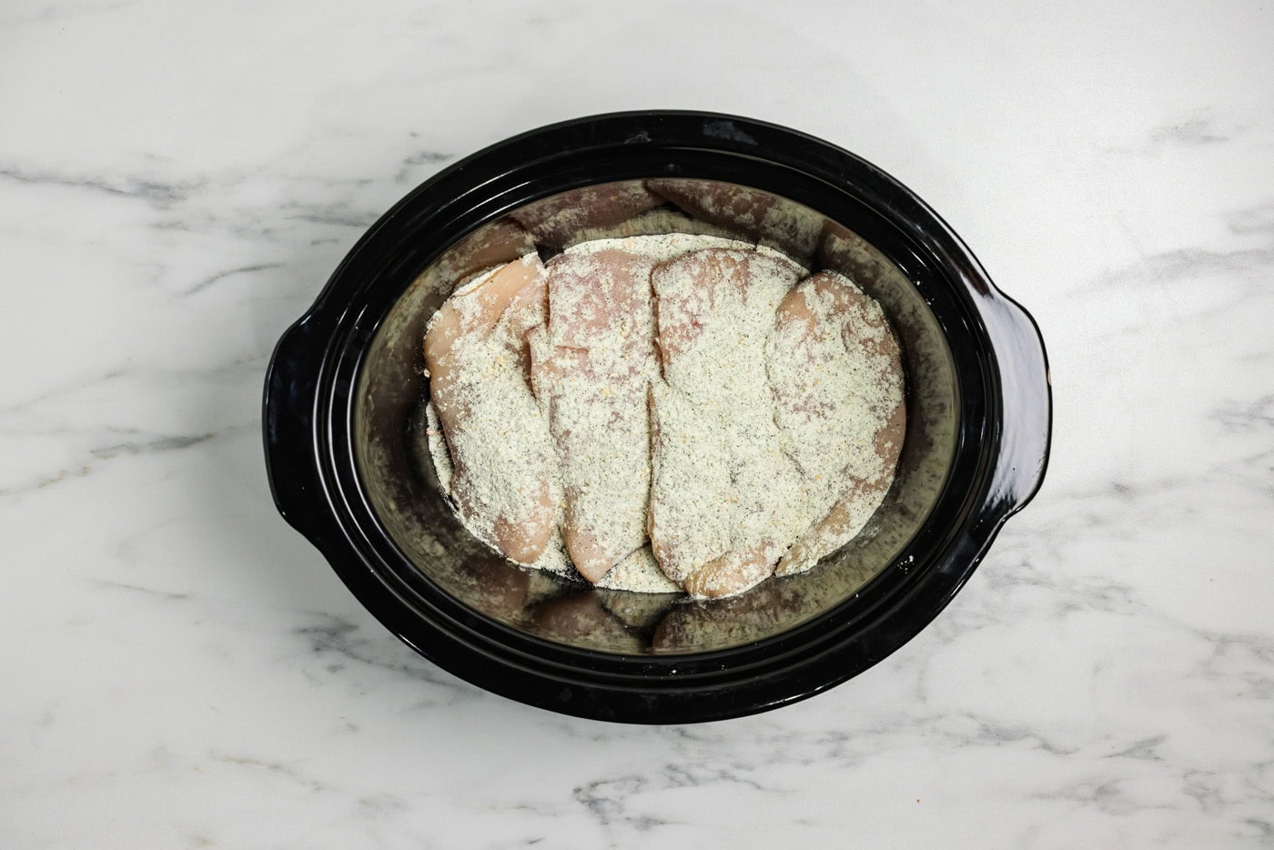 ranch seasoning srinkled over chicken breasts in a crockpot