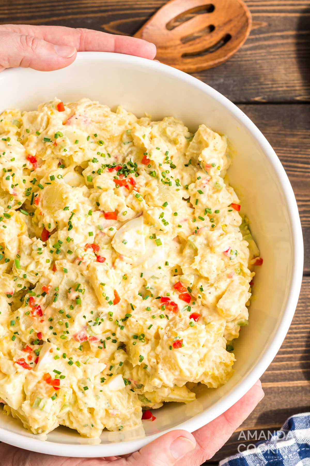 hands around large bowl of potato salad
