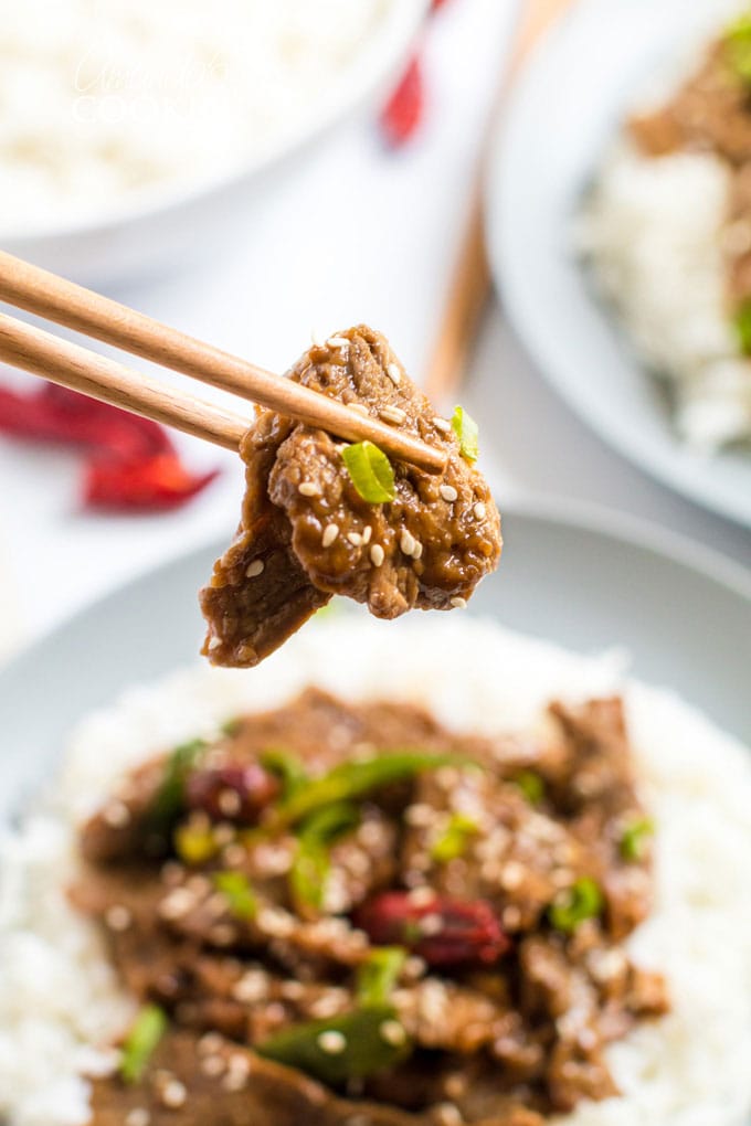 chop sticks holding a piece of mongolian beef