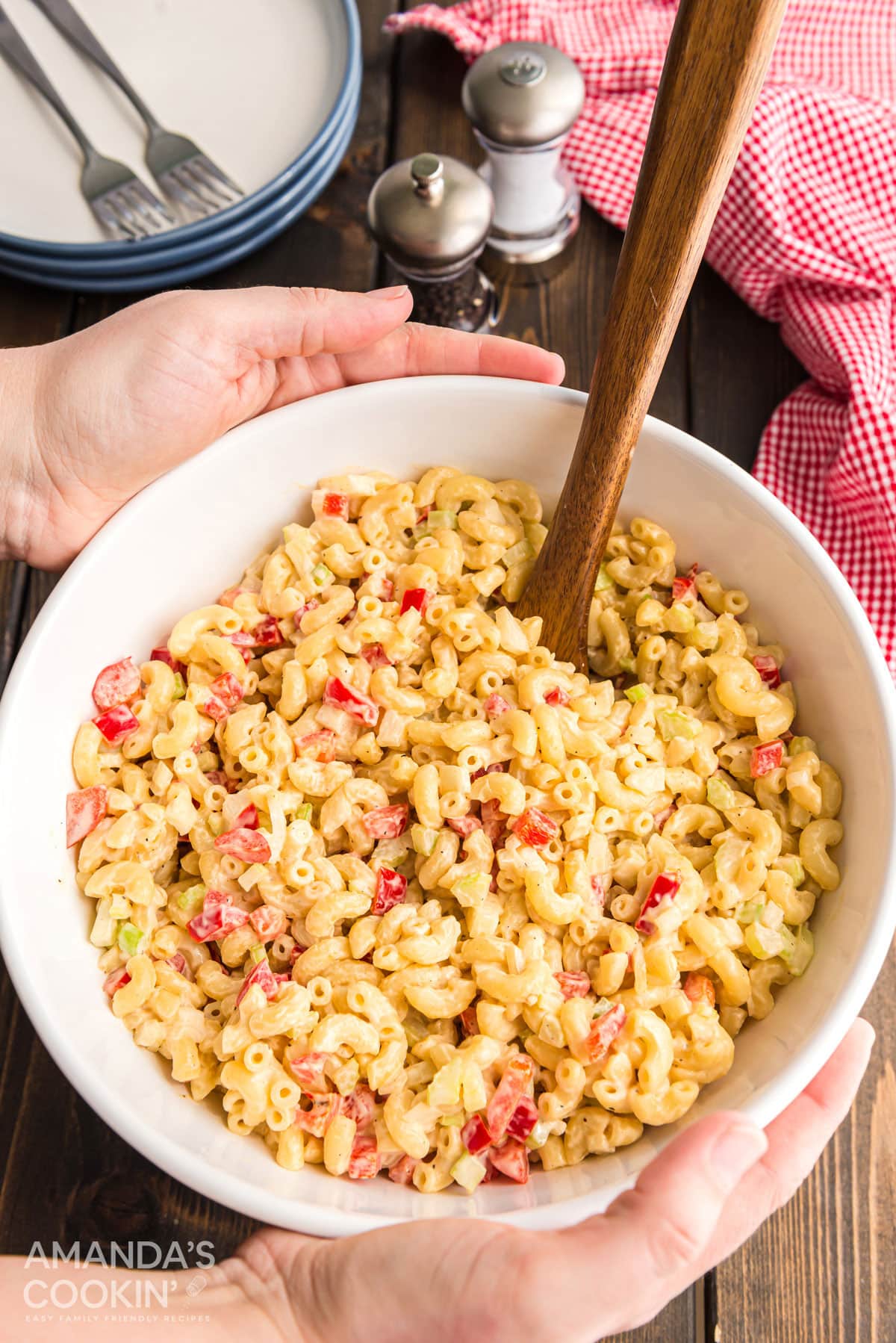 hands placing bowl of macaroni salad onto a table