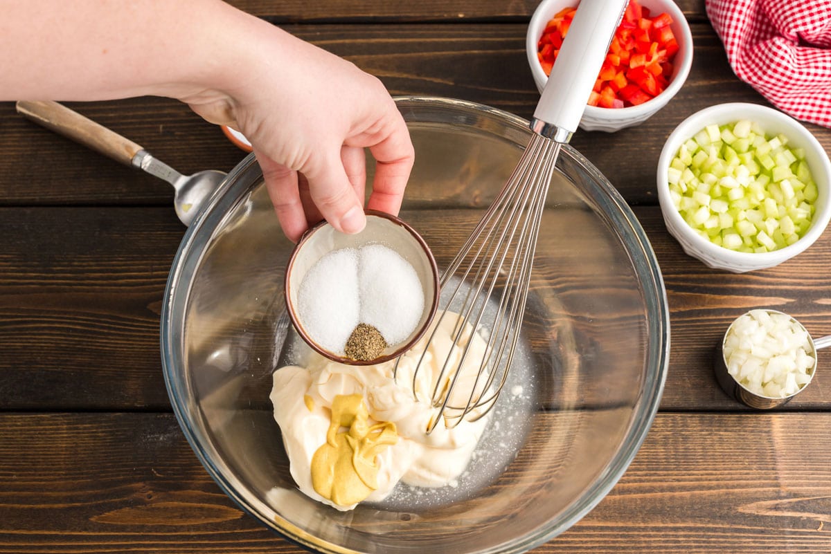adding salt and pepper to bowl with mayo and mustard