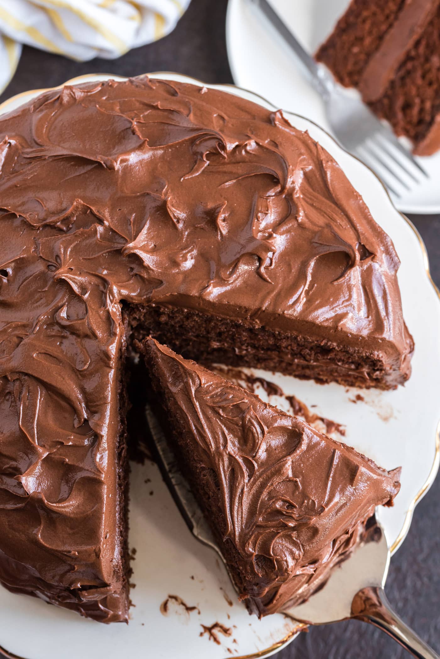 Overhead photo of a piece of Nigella's Chocolate Fudge Cake being removed from the cake