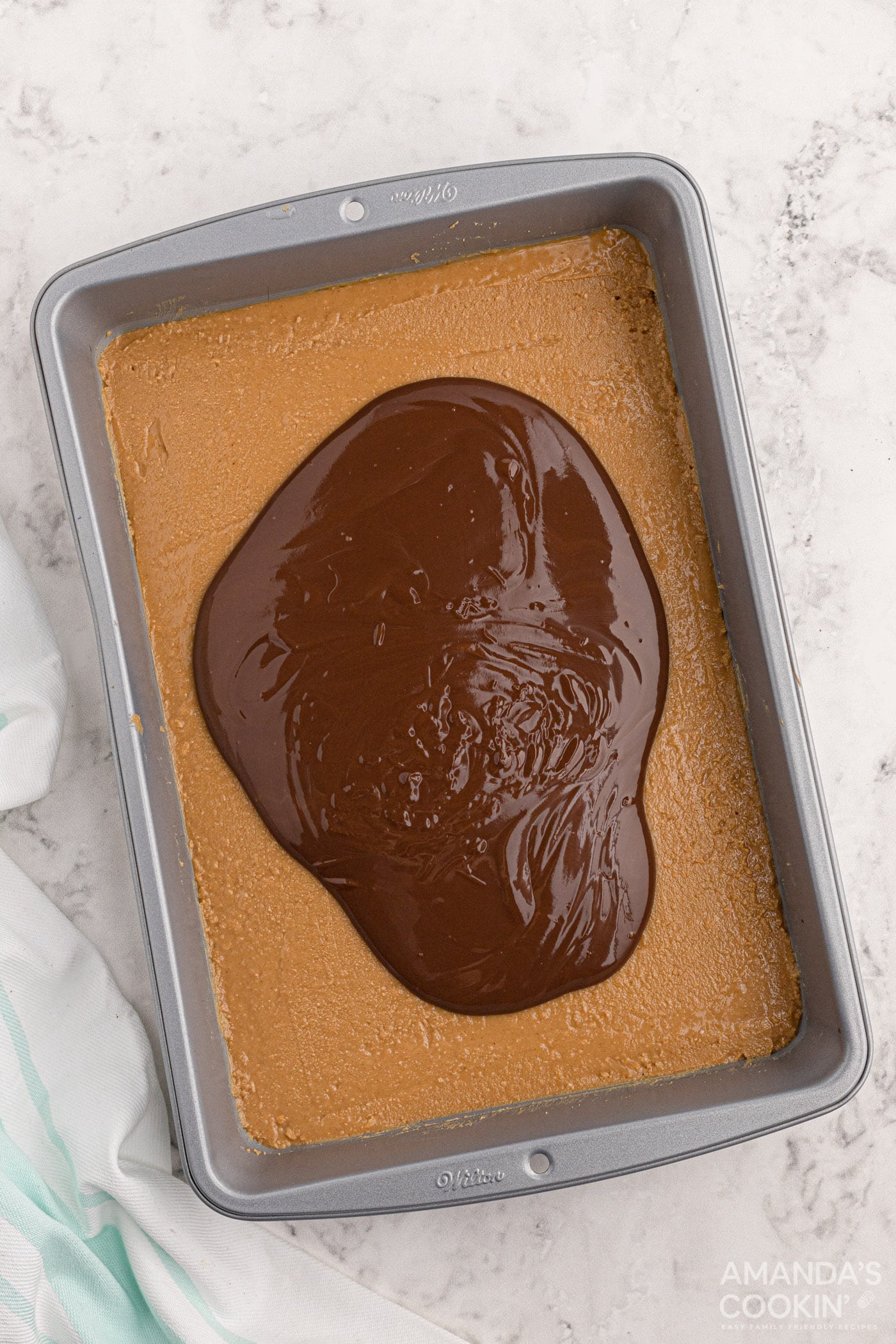 melted chocolate on peanut butter bars in pan
