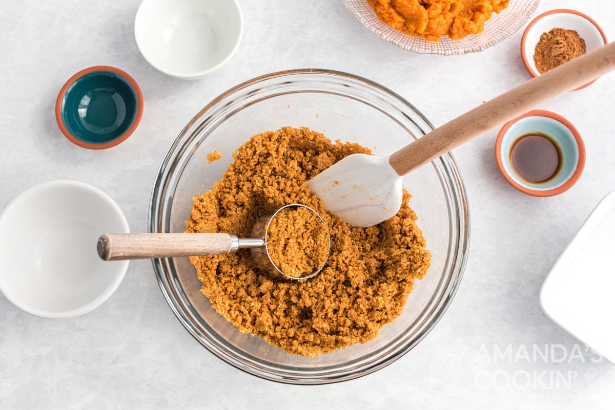 graham cracker crumb mixture with a spatula and measuring cup