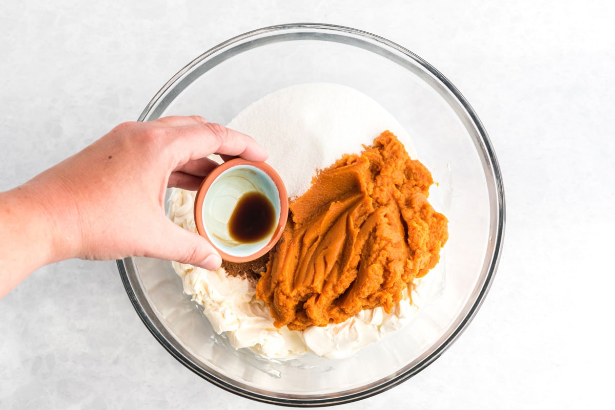 adding pumpkin cheesecake ingredients to a bowl