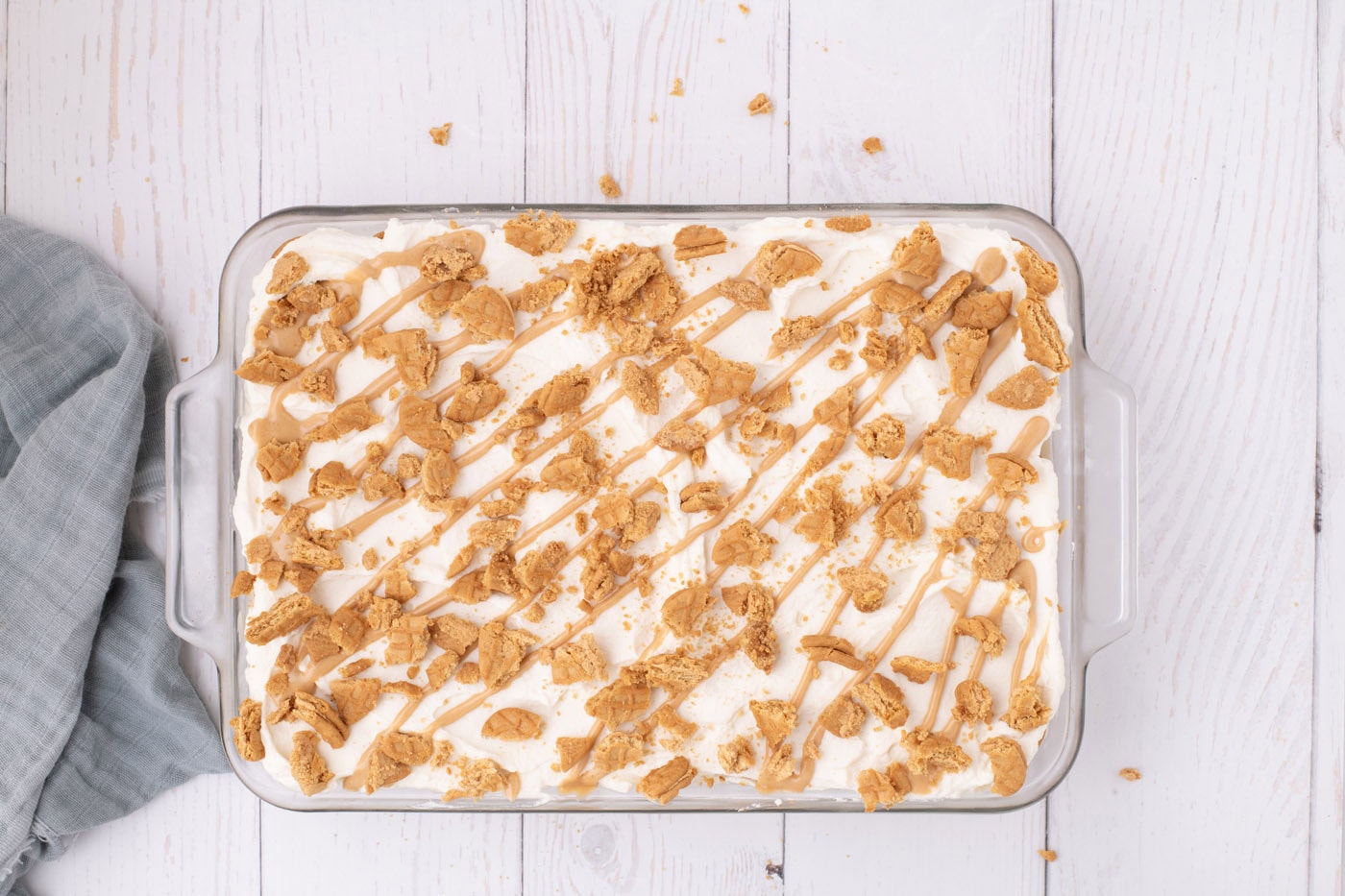Nutter butter icebox cake in a dish with crushed cookies and peanut butter drizzle on top