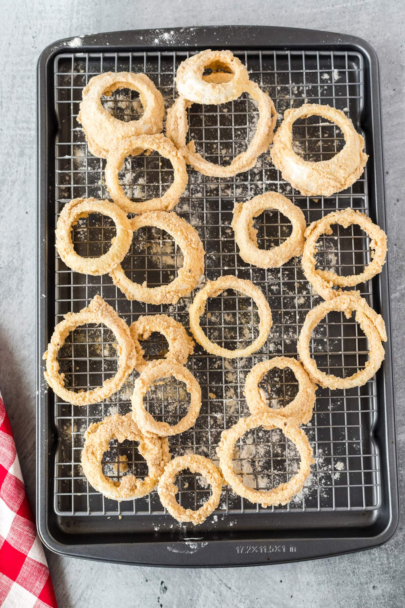 onion rings dipped in breadcrumbs on a baking sheet