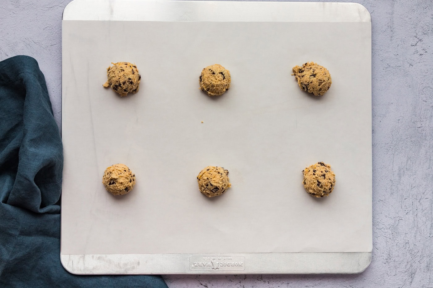 orange chocolate chip cookie dough balls on a parchment lined baking sheet