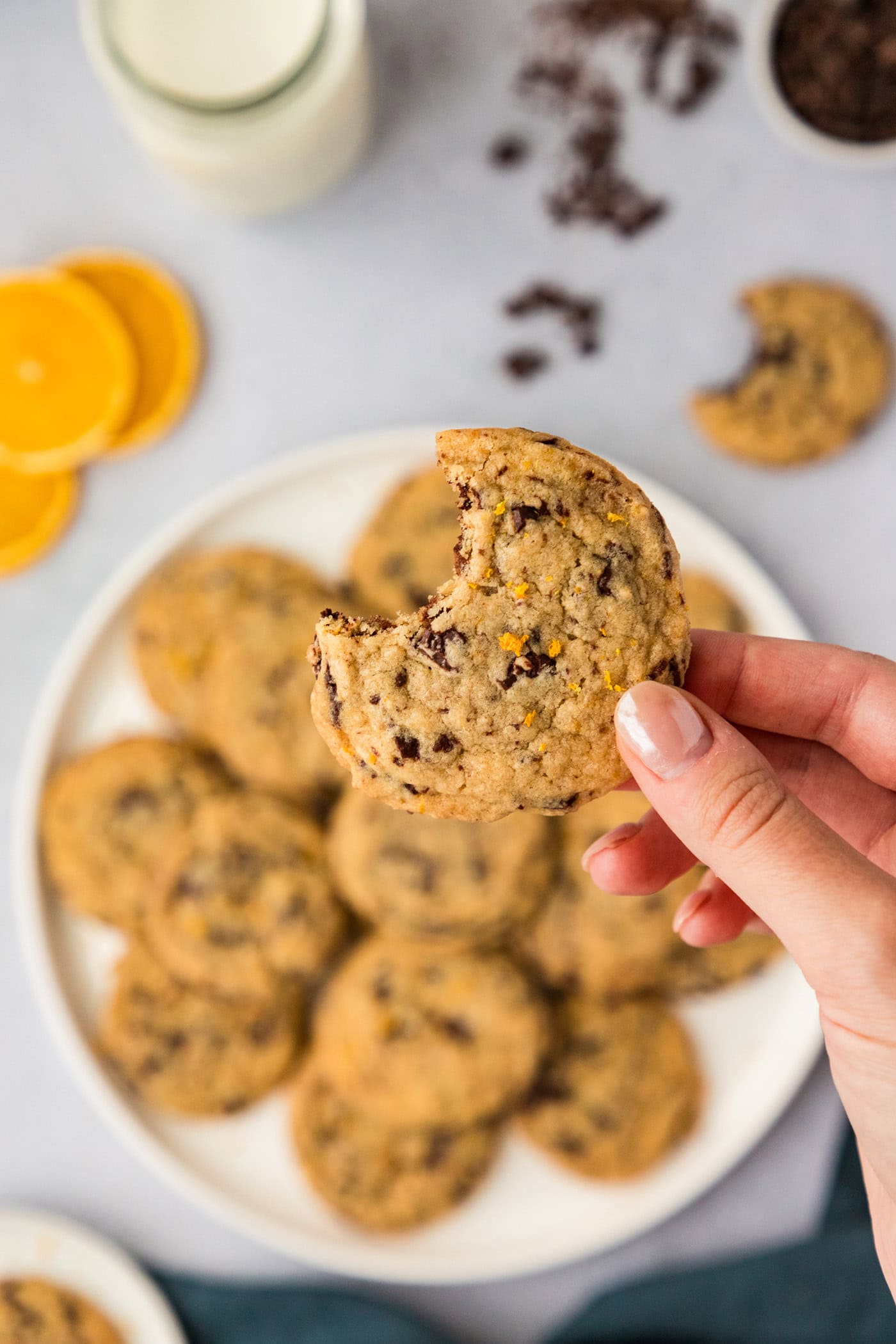 Hand holding a Orange Chocolate Chip Cookie above a plate of cookies