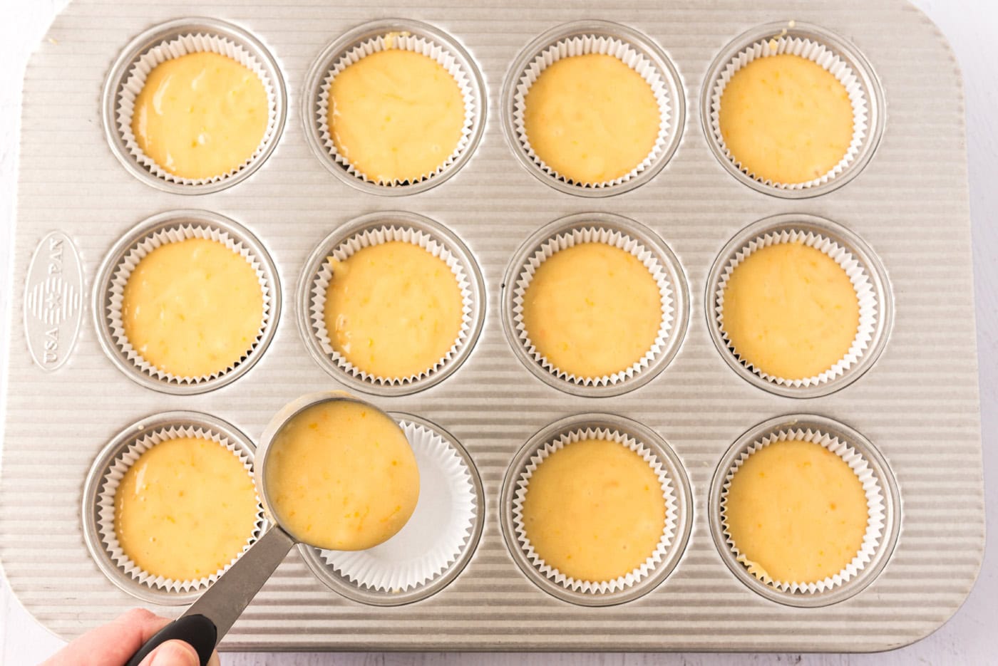 spooning cupcake batter into a pan