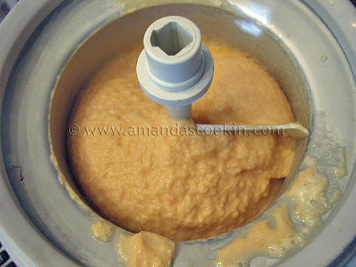 A photo of an ice cream maker filled with orange ice cream.