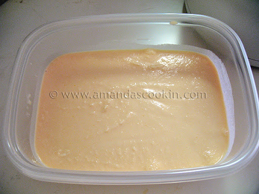 A plastic container of orange ice cream.
