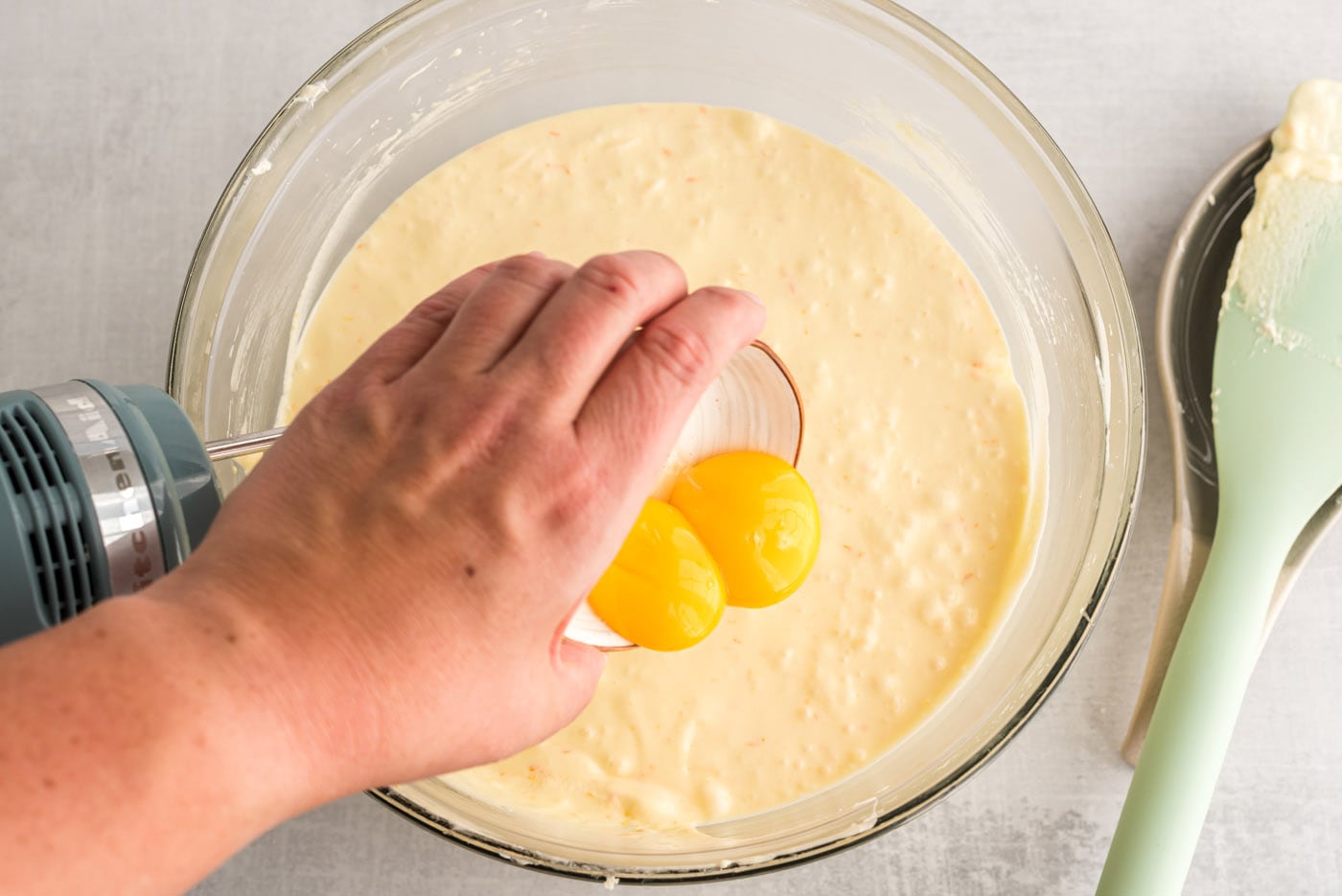 hand pouring egg yolks into pound cake batter