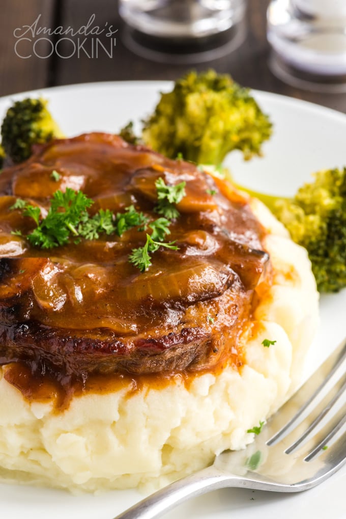 swiss steak and gravy on a pile of mashed potatoes