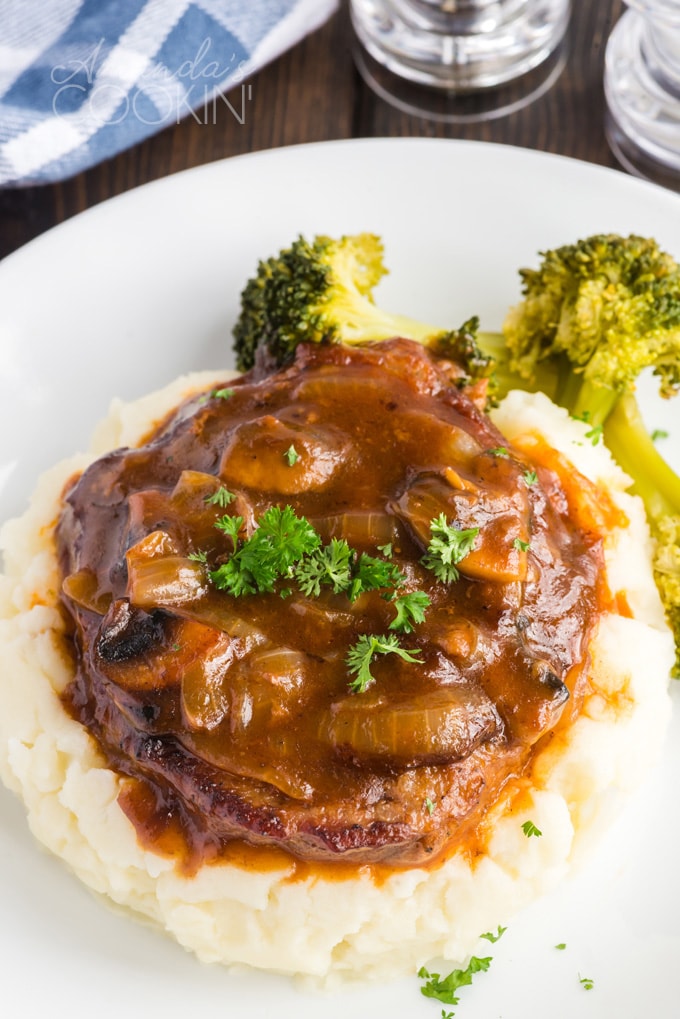 swiss steak in gravy on top of mashed potatoes