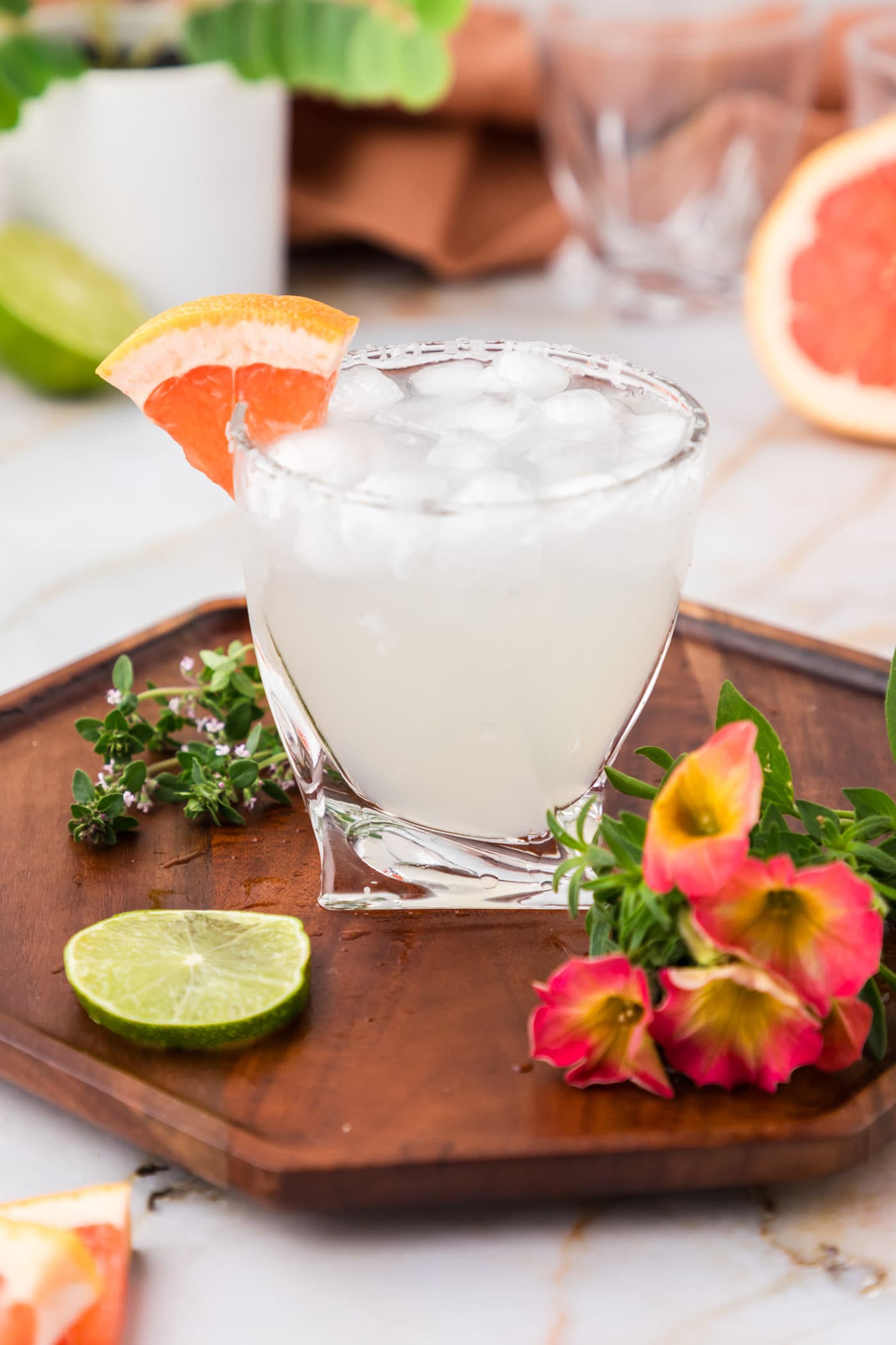 Paloma on a wooden tray with flowers and a lime wheel