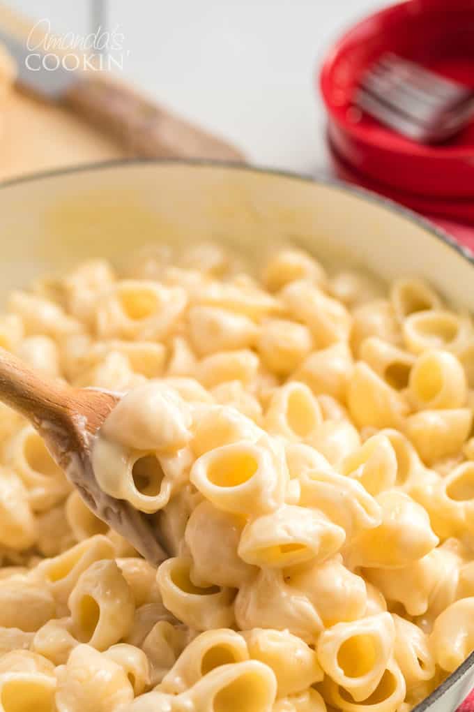 bowl of homemade panera mac and cheese being stirred with wooden spoon