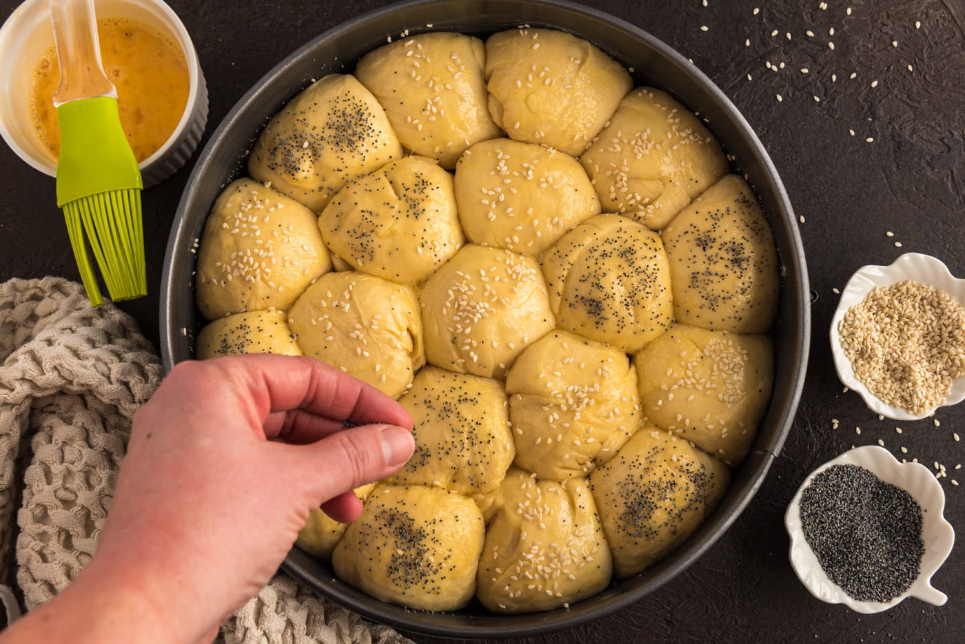 sprinkling bread rolls with poppy seeds and sesame seeds