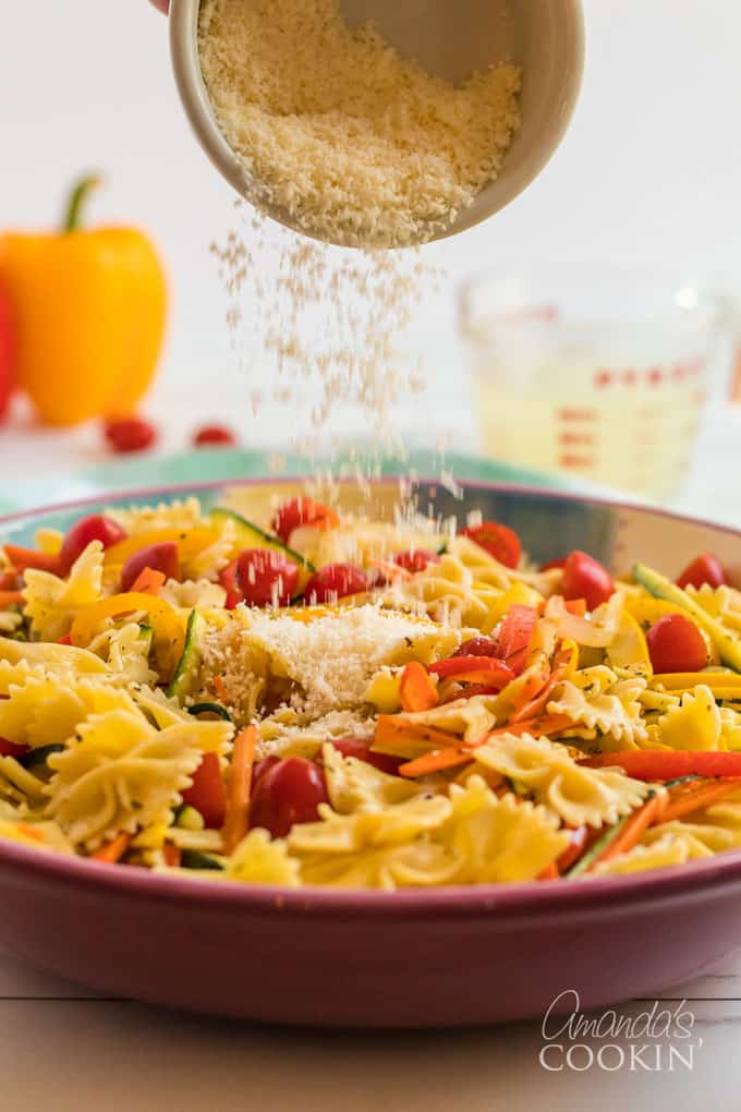 parmesan cheese being sprinkled over pasta primavera