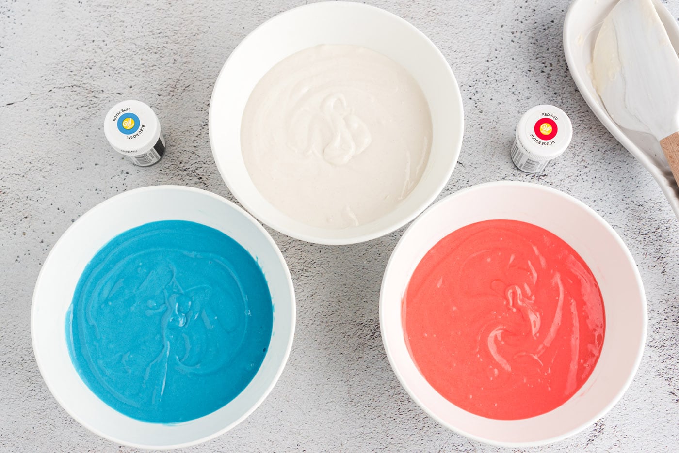 colored cake batter in bowls